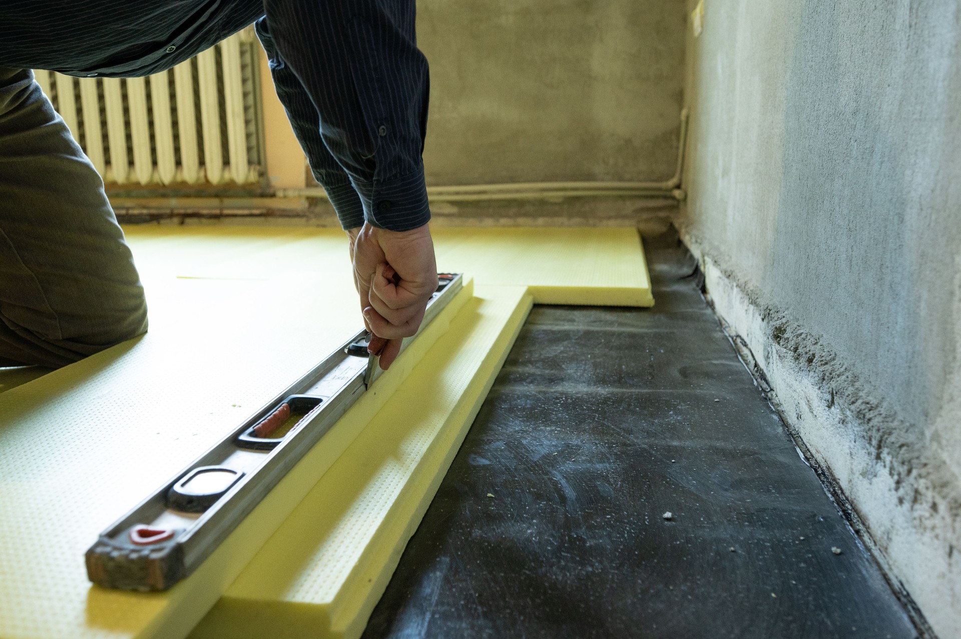 Close-up of the master cuts the size of expanded polystyrene on the floor, the process of floor insulation in the house.
