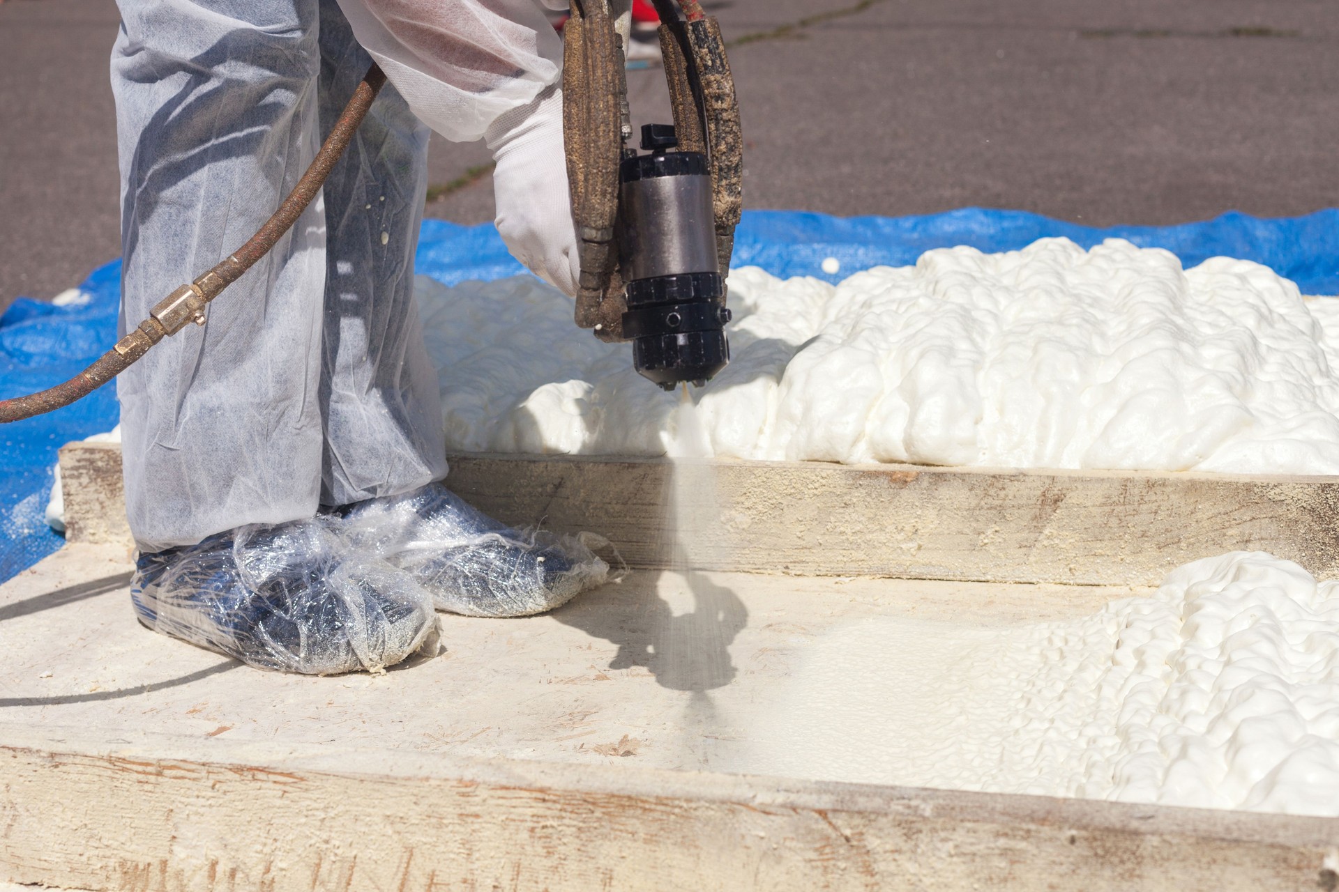 Technician spraying foam insulation using Plural Component Spray Gun. Spraying polyurethane foam for roof